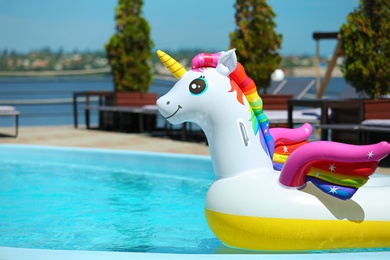 Funny inflatable unicorn ring floating in swimming pool on sunny day, outdoors. Space for text