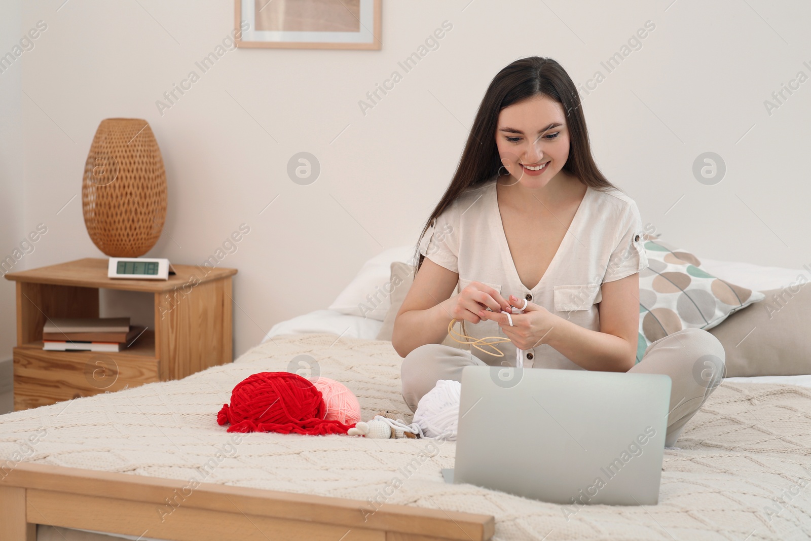 Photo of Young woman learning to knit with online course at home, space for text. Handicraft hobby