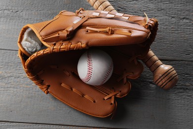 Photo of Baseball glove, bat and ball on grey wooden table, closeup