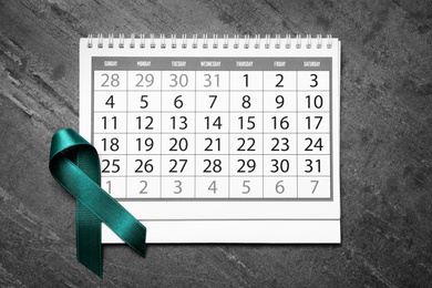 Flat lay composition with teal ribbon and calendar on grey background