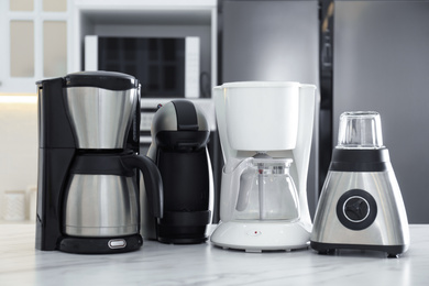 Photo of Set of modern home appliances on white marble table in kitchen