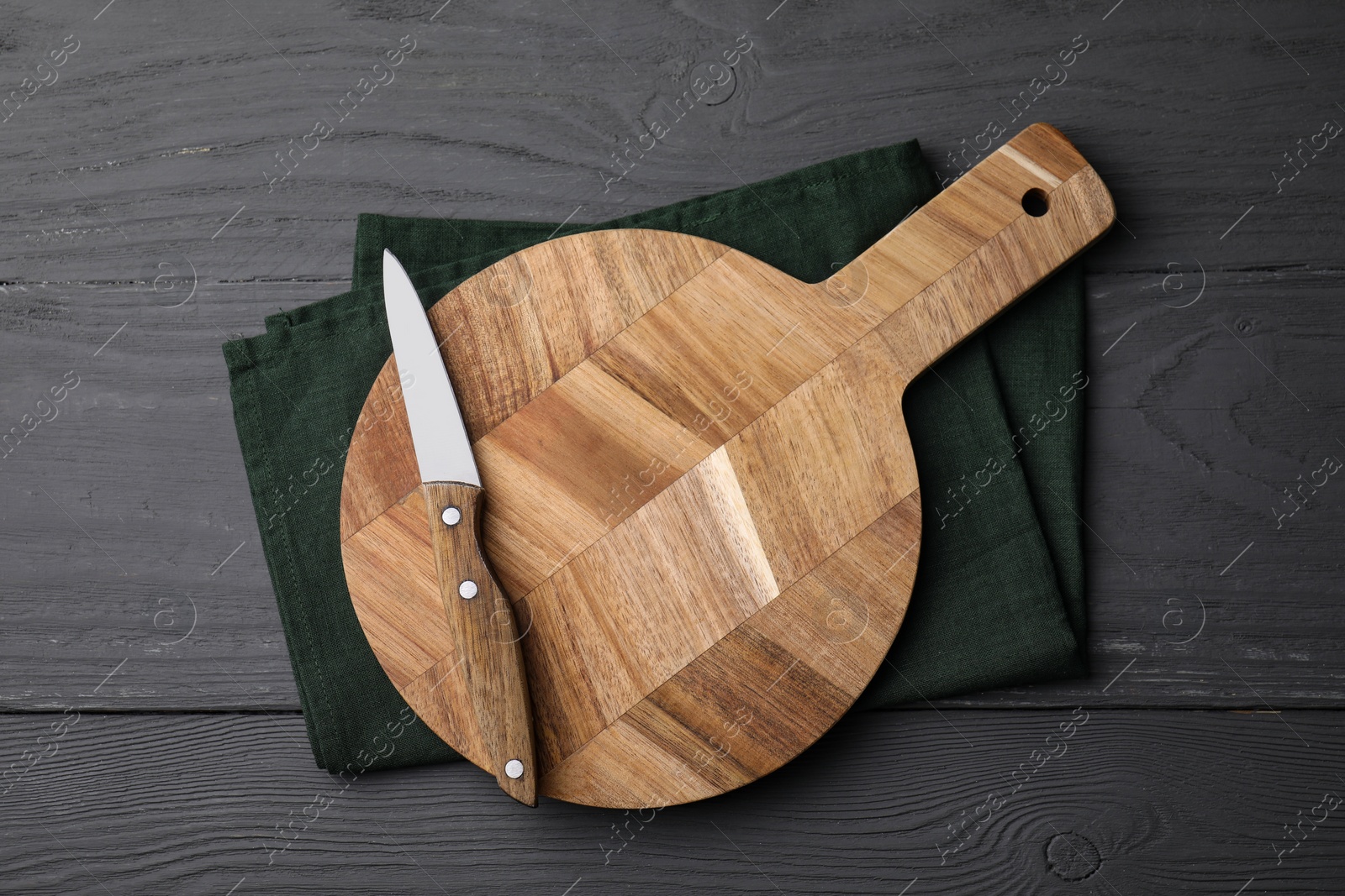 Photo of Wooden board, knife and napkin on grey table, top view