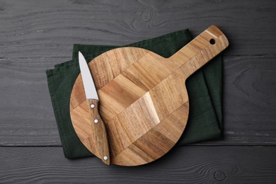 Photo of Wooden board, knife and napkin on grey table, top view