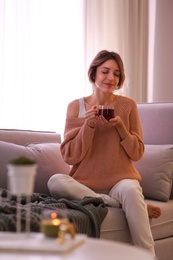 Photo of Beautiful young woman with cup of tea relaxing at home. Cozy atmosphere