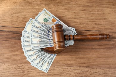 Photo of Judge's gavel and money on wooden table, top view