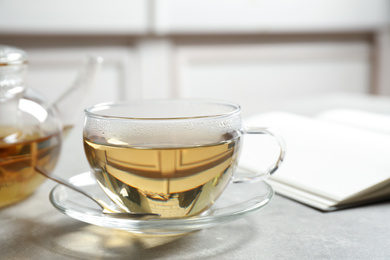 Tasty hot green tea in cup on grey table, closeup