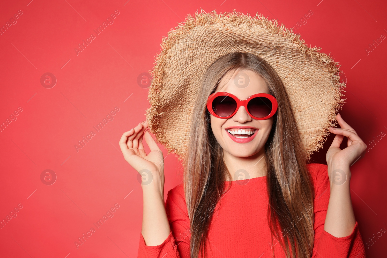 Photo of Young woman wearing stylish sunglasses and hat on red background. Space for text