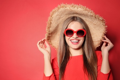 Photo of Young woman wearing stylish sunglasses and hat on red background. Space for text