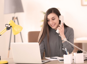 Young woman talking on phone at workplace