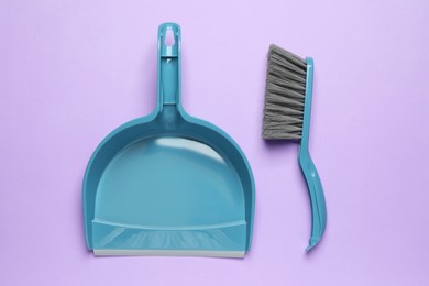 Photo of Plastic hand broom and dustpan on violet background, flat lay