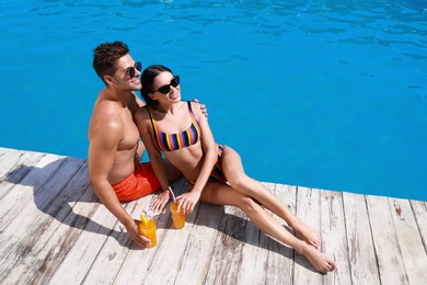 Photo of Woman in bikini with boyfriend near outdoor pool. Happy young couple