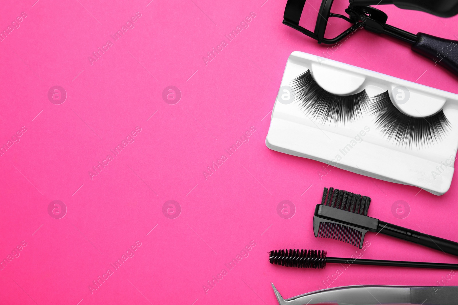 Photo of Flat lay composition with fake eyelashes, brushes and tools on pink background. Space for text