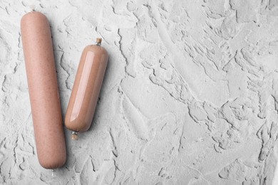 Photo of Delicious liver sausages on white textured table, flat lay. Space for text