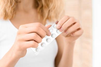 Photo of Young woman holding blister pack with pills, closeup