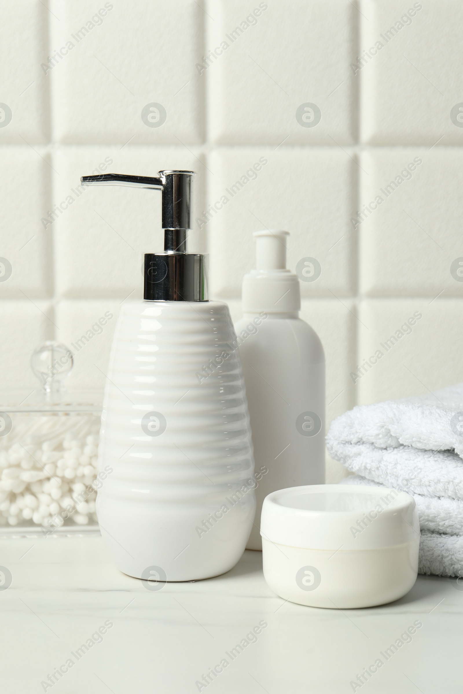 Photo of Different bath accessories and personal care products on white table near tiled wall