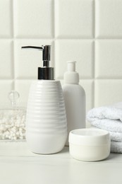 Photo of Different bath accessories and personal care products on white table near tiled wall