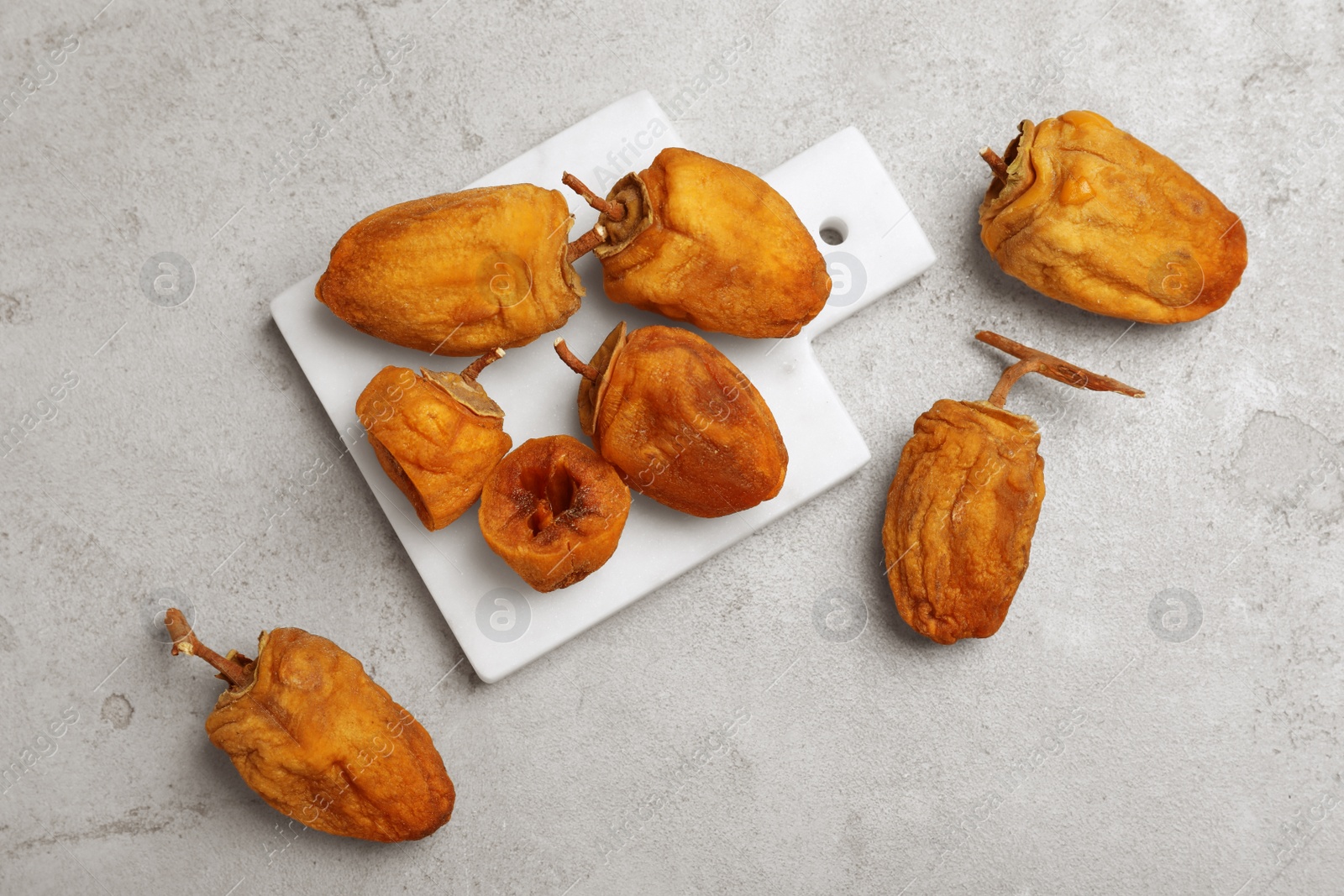 Photo of Many tasty dried persimmon fruits on light table, flat lay