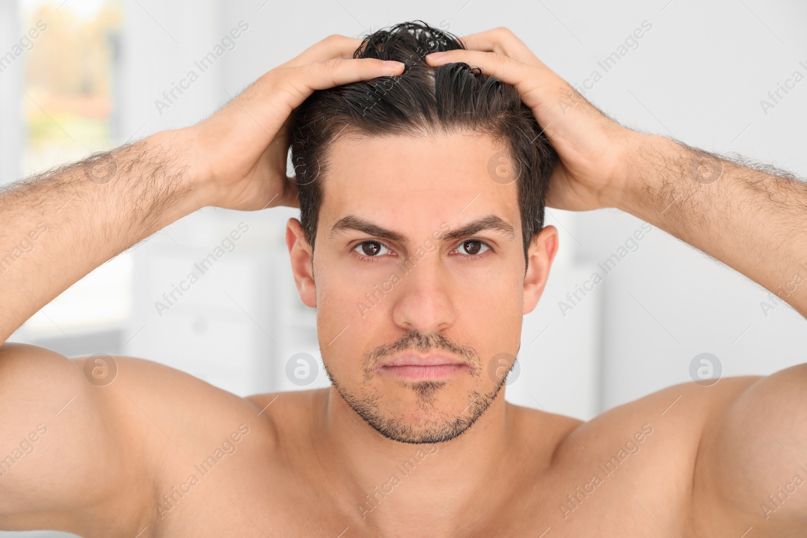 Photo of Handsome man applying hair conditioner in bathroom