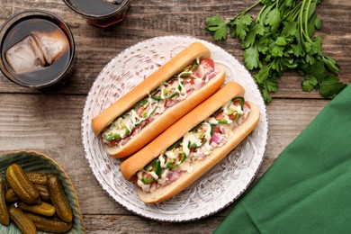 Photo of Delicious hot dogs with onion, chili pepper and sauce served on wooden table, flat lay