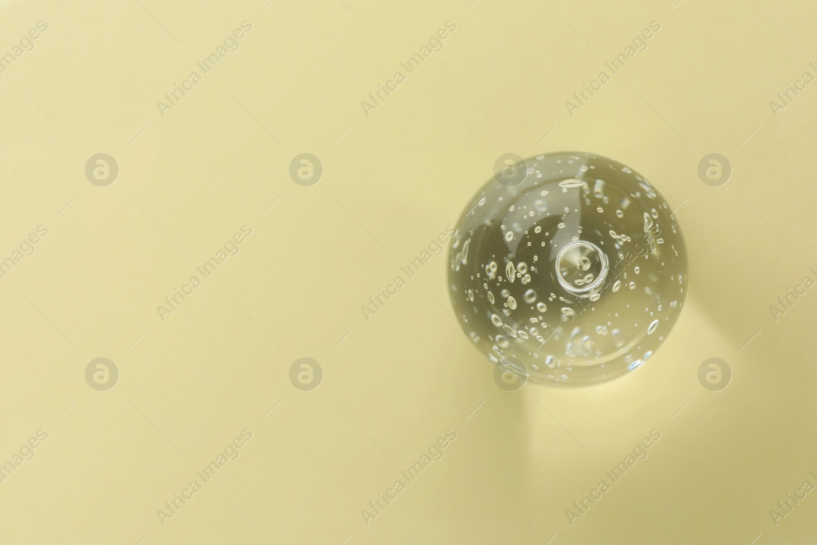 Photo of Clear cosmetic gel on yellow background, top view. Space for text