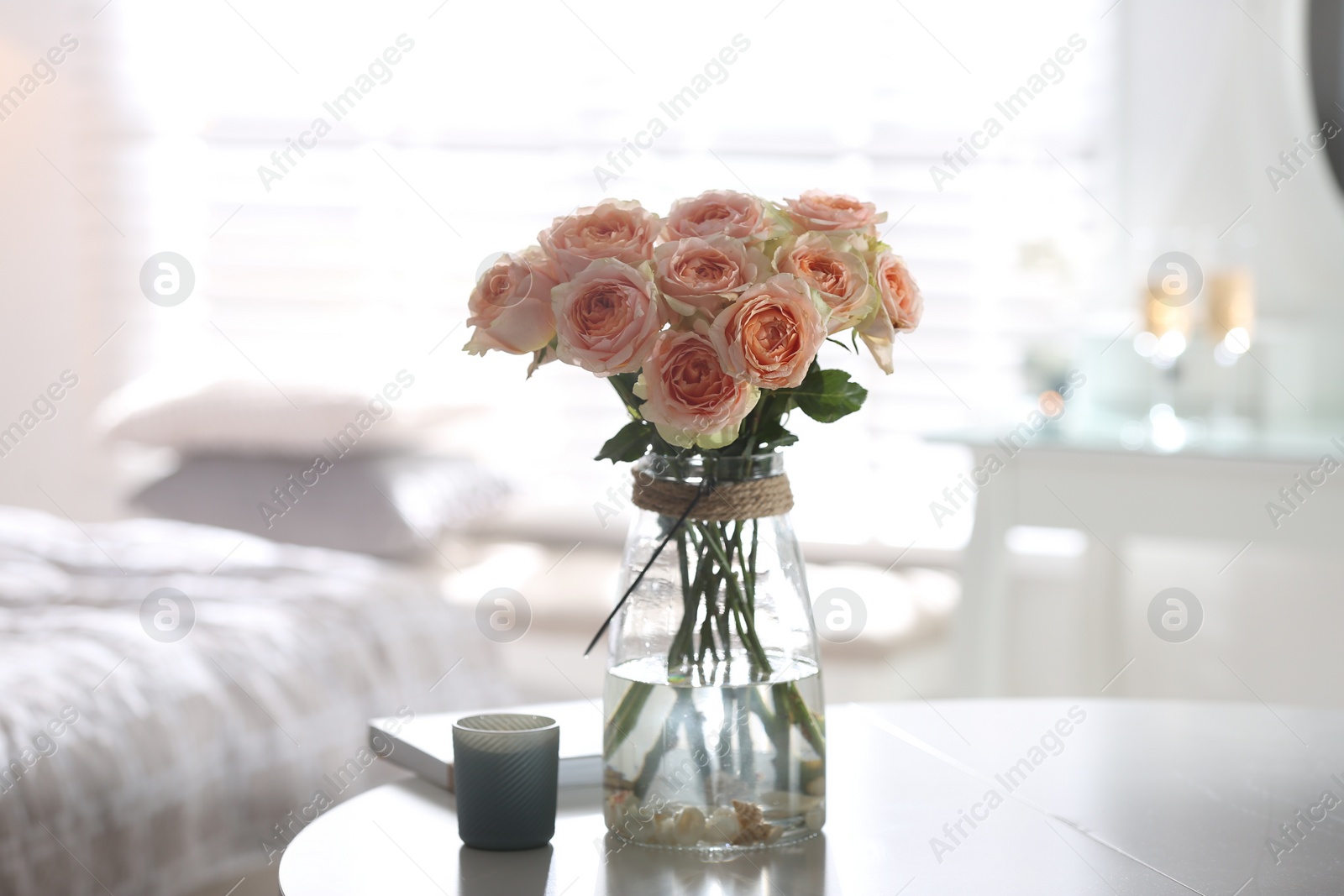 Photo of Glass vase with beautiful flowers on table in modern room interior