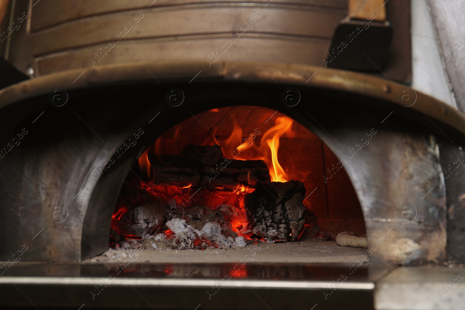 Photo of Oven with burning firewood and tasty pizza in restaurant kitchen