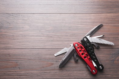 Photo of Modern compact portable multitool on wooden table, top view. Space for text