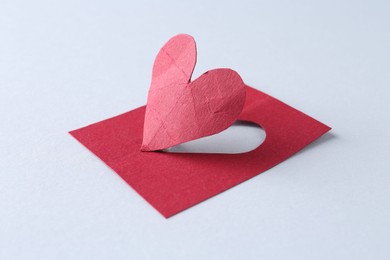 One red paper heart on gray background