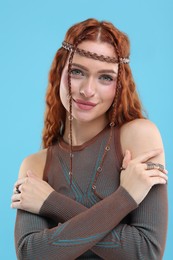 Beautiful young hippie woman on light blue background