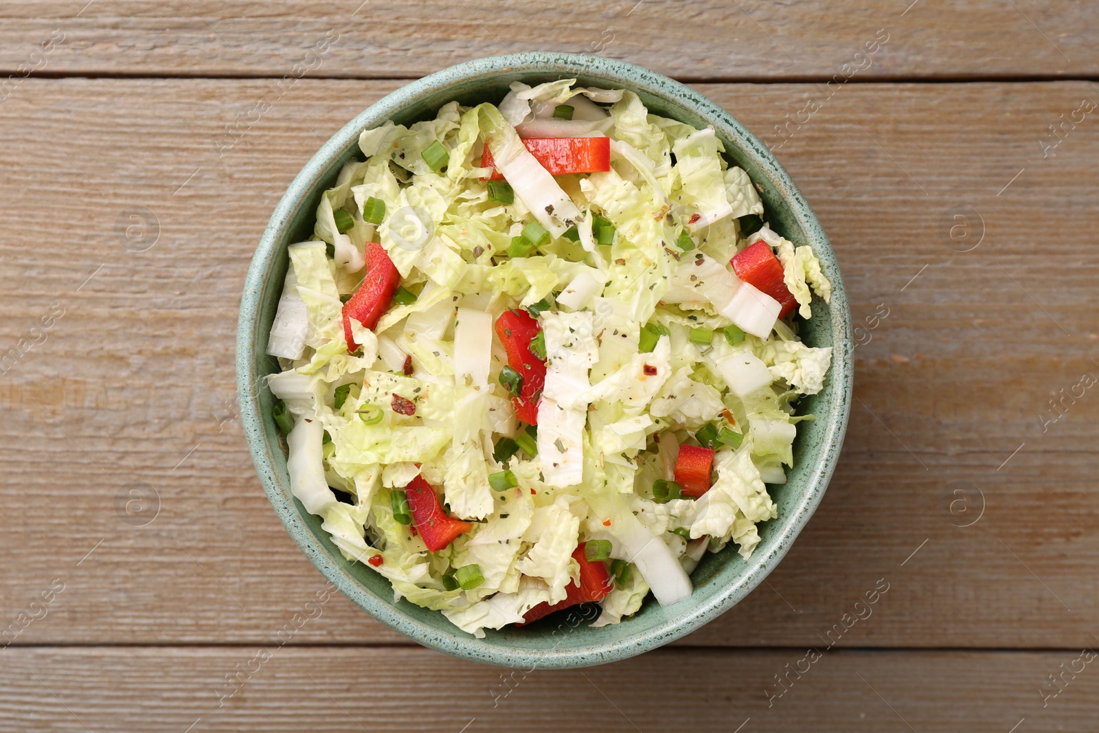 Photo of Tasty salad with Chinese cabbage, bell pepper and green onion in bowl on wooden table, top view