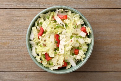 Photo of Tasty salad with Chinese cabbage, bell pepper and green onion in bowl on wooden table, top view