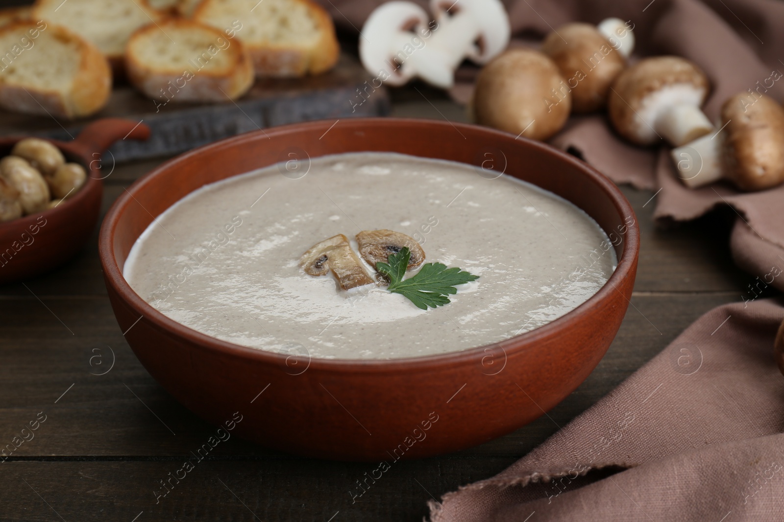 Photo of Delicious mushroom cream soup with parsley on wooden table