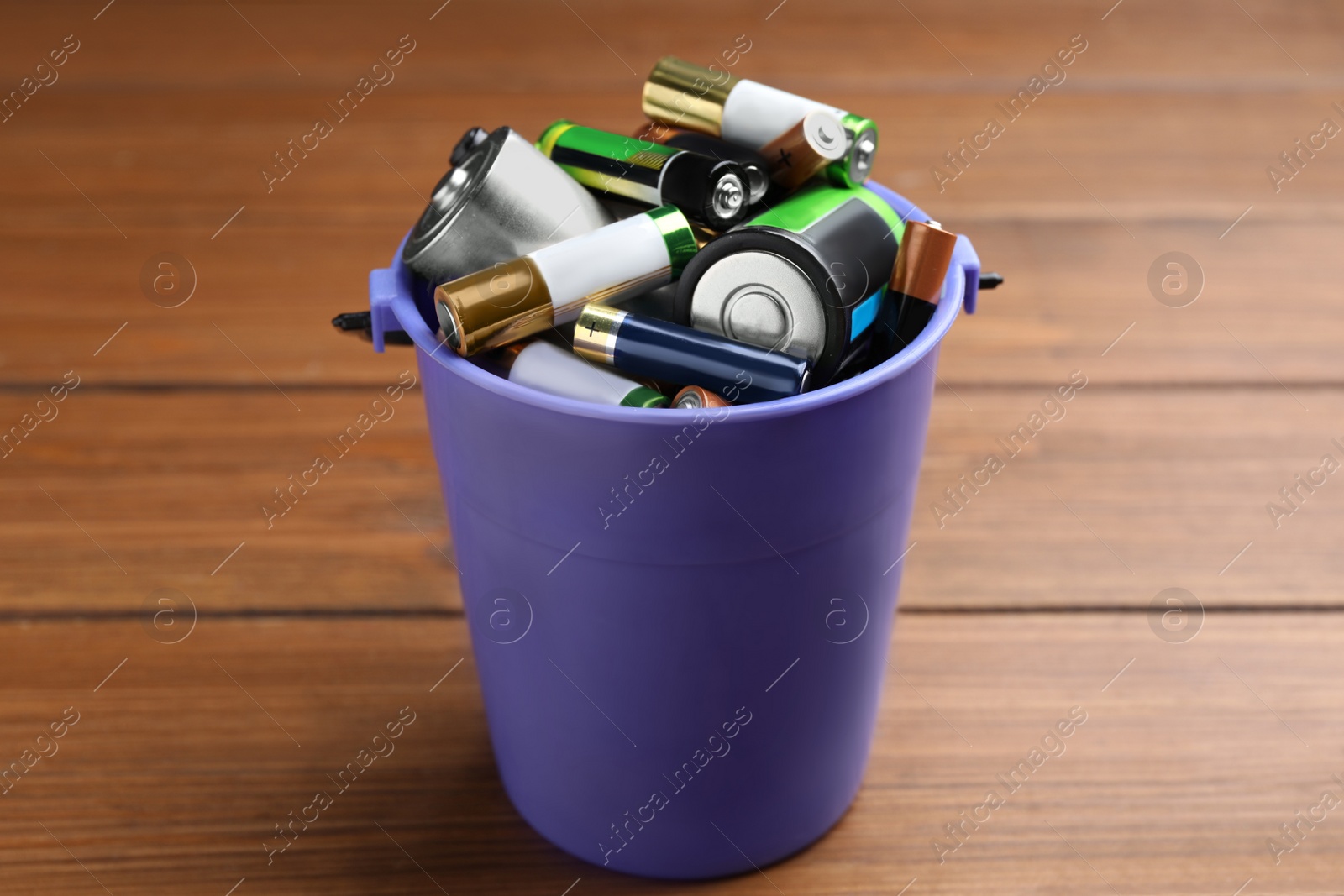 Image of Used batteries in bucket on wooden table