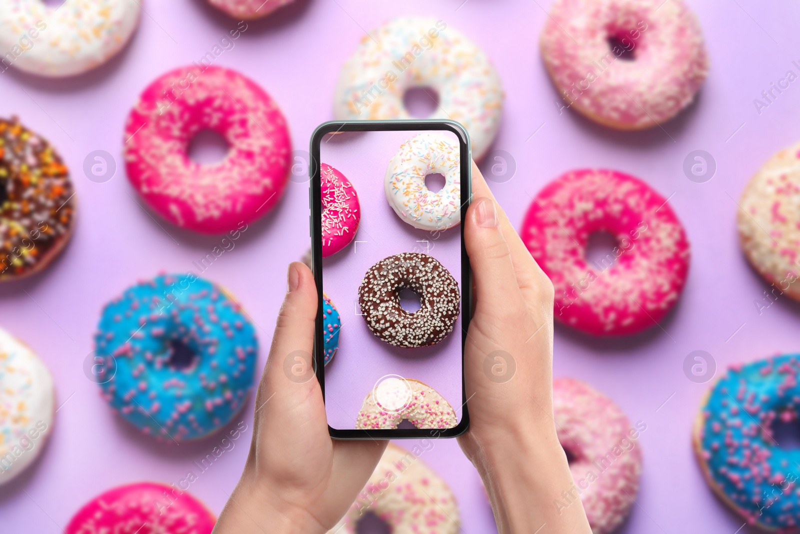 Image of Woman taking picture of delicious doughnuts on violet background, top view