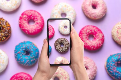 Image of Woman taking picture of delicious doughnuts on violet background, top view