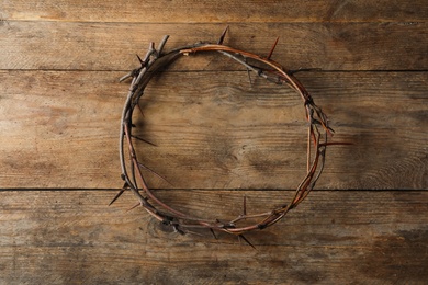 Photo of Crown of thorns on wooden background, top view. Easter attribute
