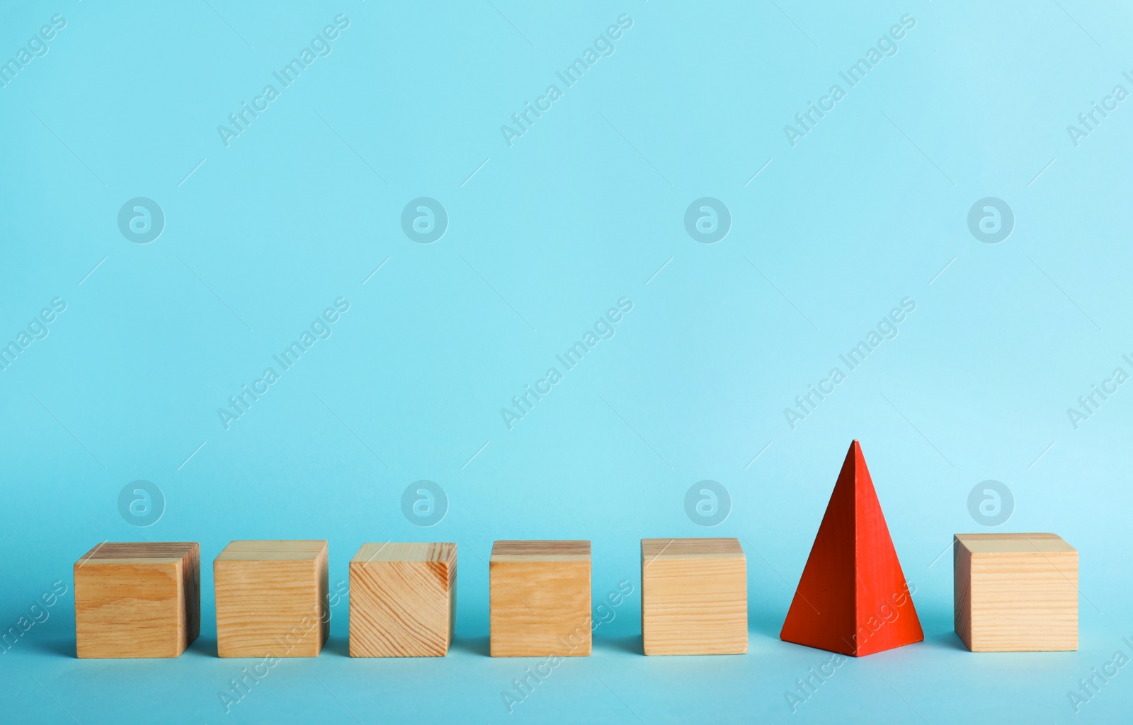 Photo of Row of wooden cubes and red pyramid on color background. Be different