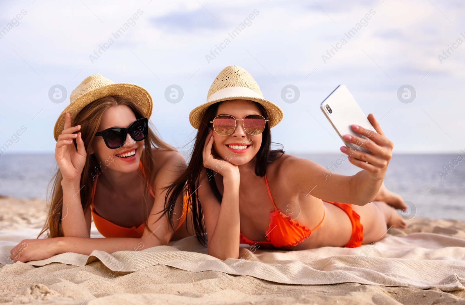 Photo of Young couple in bikini taking selfie on beach