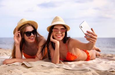 Young couple in bikini taking selfie on beach