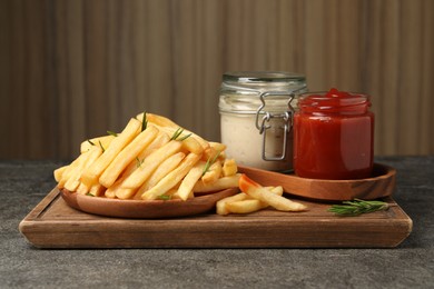 Delicious french fries served with sauces on grey textured table