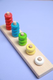 Photo of Stacking and counting game wooden pieces on violet background. Educational toy for motor skills development