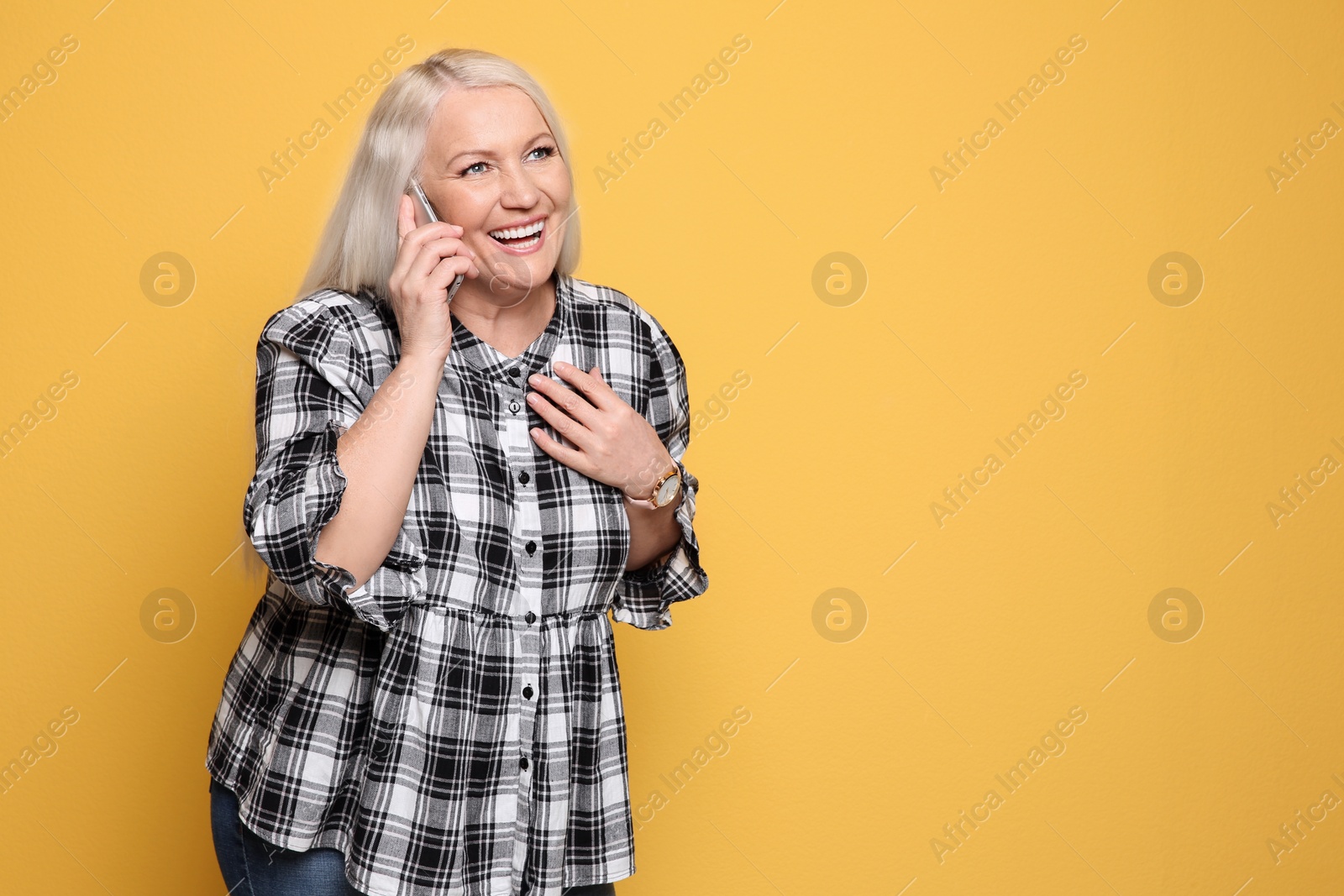 Photo of Mature woman talking on mobile phone against color background