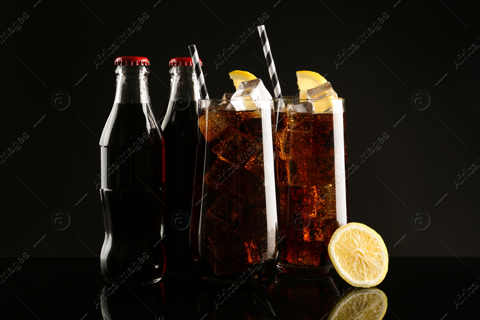 Photo of Bottles and glasses of refreshing soda water on black background