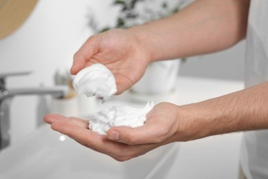 Photo of Man holding shaving foam in bathroom, closeup