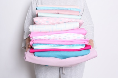 Photo of Woman holding stack of clean bed linens on white background, closeup