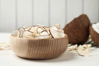 Photo of Tasty coconut chips on white wooden table