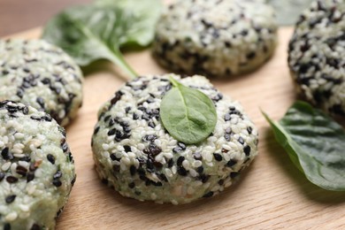 Photo of Tasty vegan cutlets with sesame seeds and spinach on wooden table, closeup