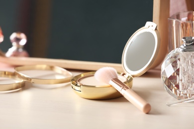 Photo of Pocket powder with brush and perfume bottle on dressing table