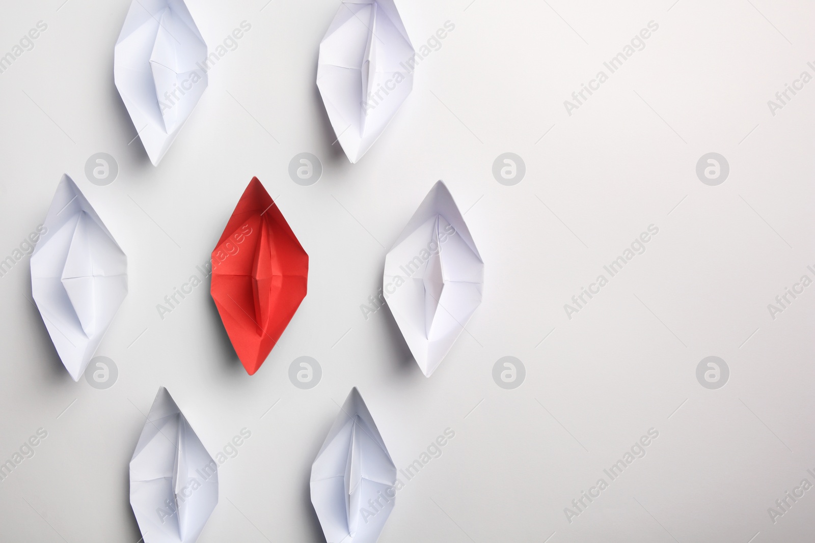 Photo of Red paper boat among others on white background, flat lay with space for text. Uniqueness concept