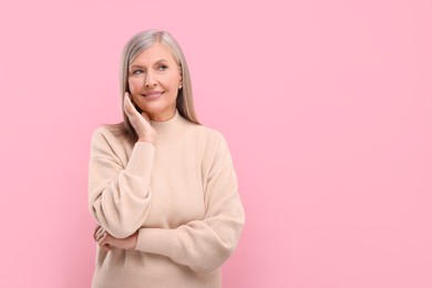 Photo of Portrait of beautiful middle aged woman on pink background, space for text